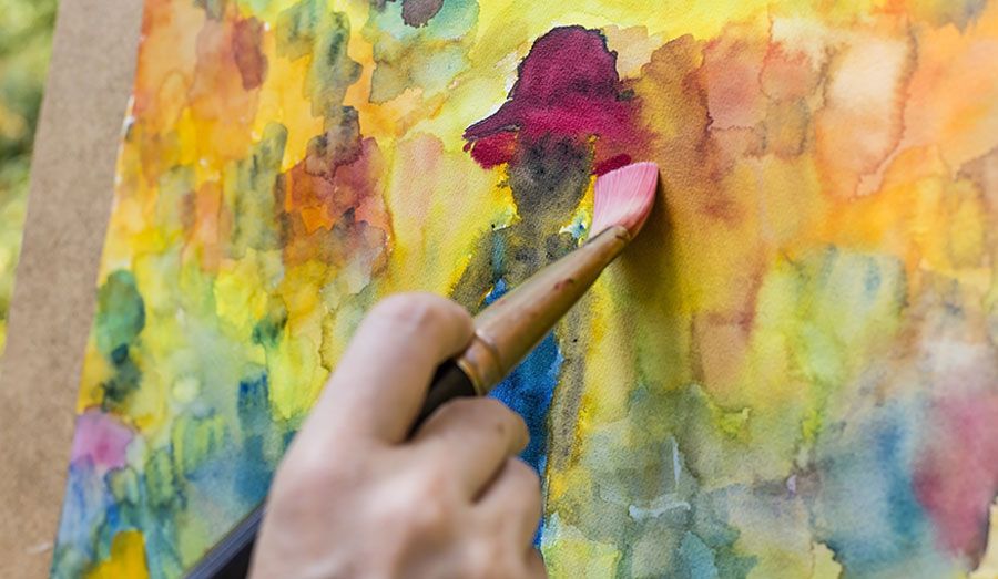Kunsttherapie - Person malt mit Pinsel auf Leinwand